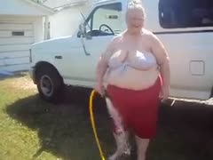 Outside, a large, attractive woman with sagging breasts, a grandmother, is fiddling with pantyhose.